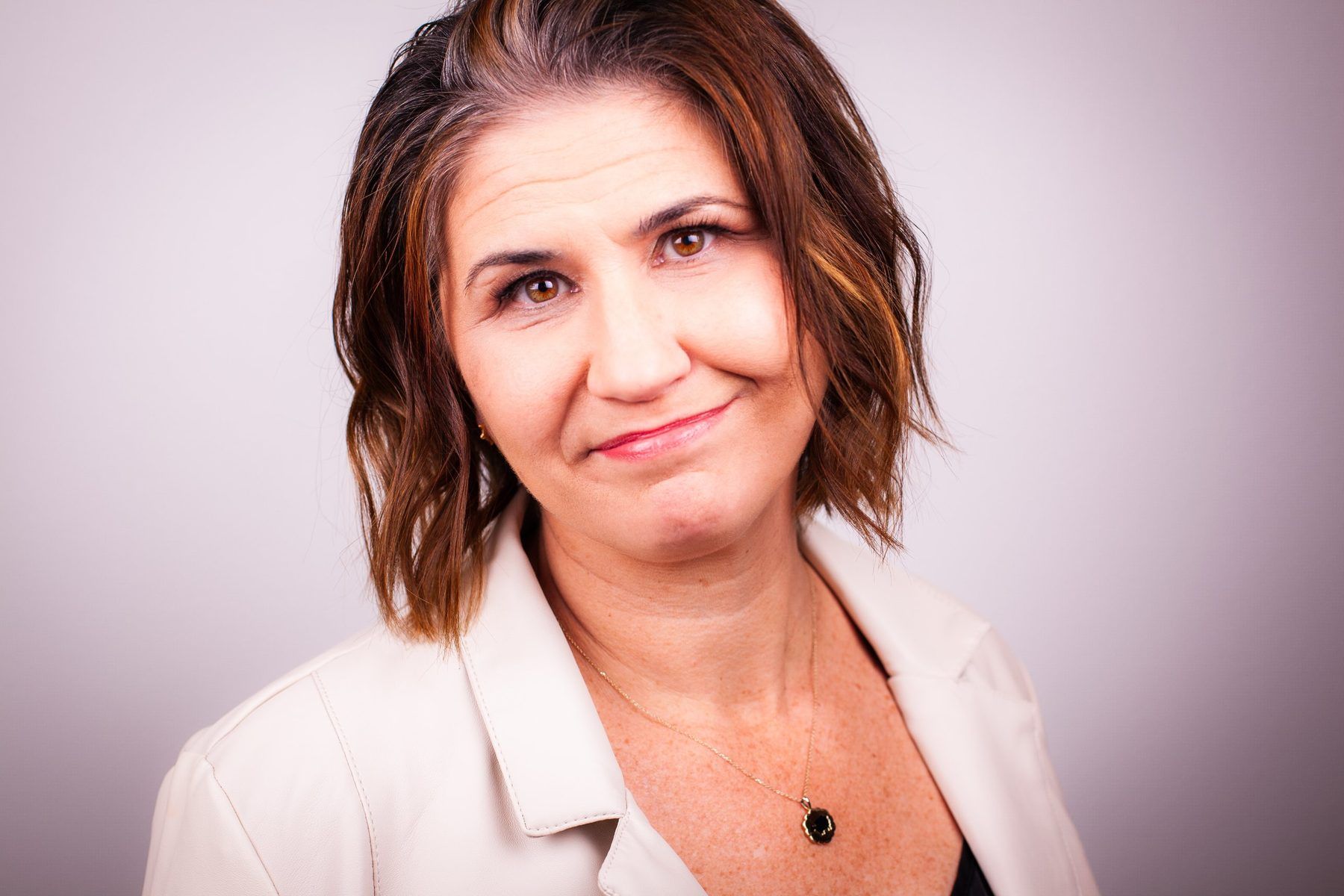 Lori Lackland in a cream jacket, smiling slightly at the camera.